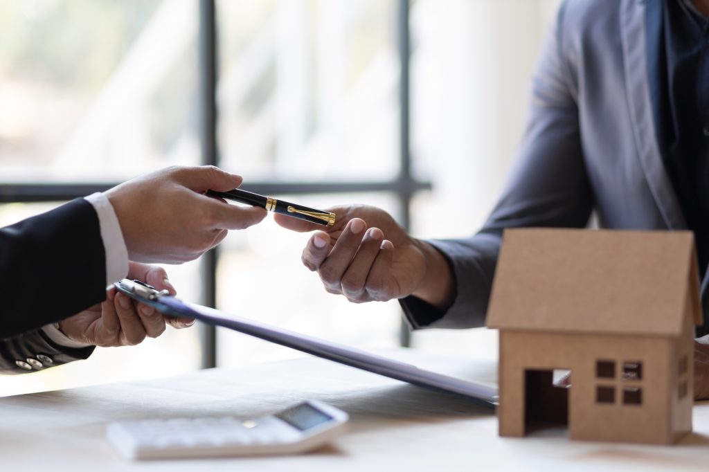 Businessmen and real estate agents discussing documents signing a legal purchase of a house.