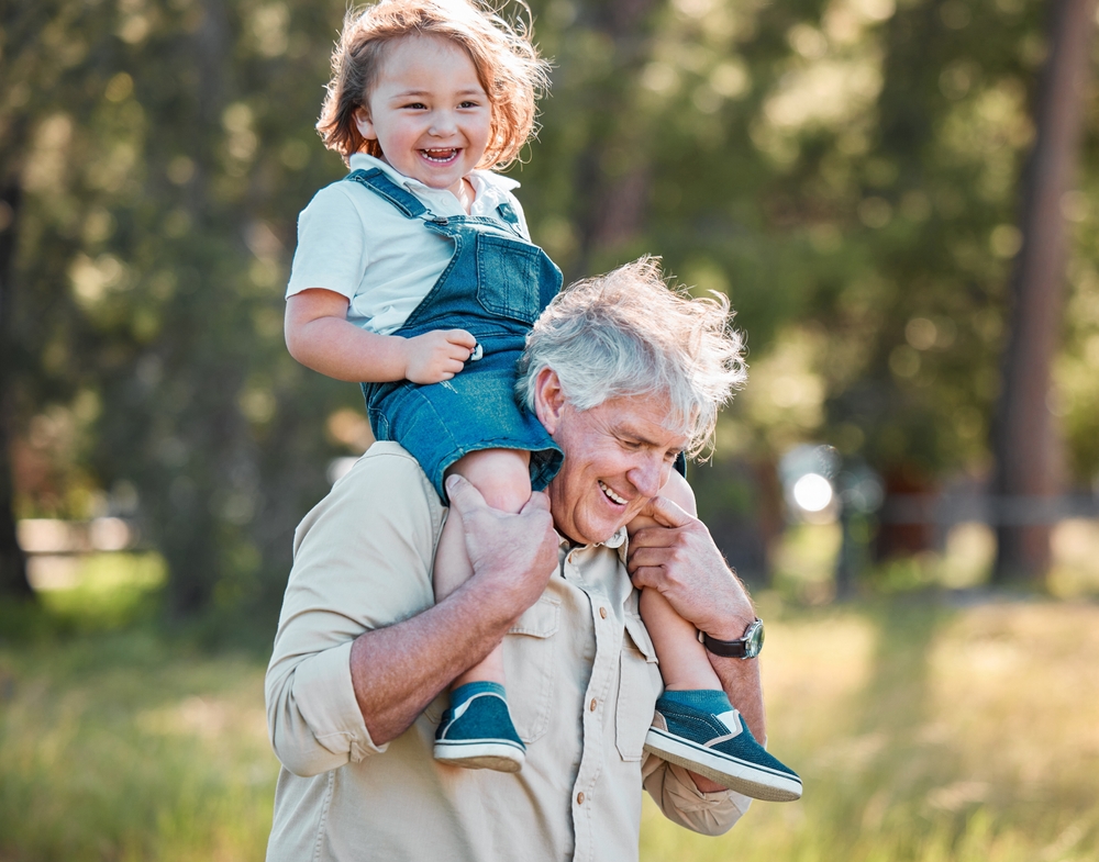 An older man carrying a young child on his shoulders.